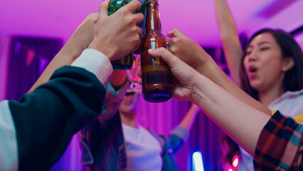 Closeup hands multiethnic young adult Asia friend wear futuristic neon glowing glasses dance and drink alcohol beer fun hangout party in living room night indoor home. Disco lights illuminating house.