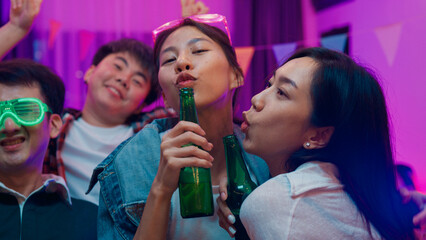 Diverse group adult Asia friend look at camera shooting video photo on mobile app dance and drink alcohol beer fun hangout party in living room night indoor home. Disco neon lights illuminating house.