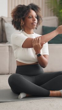 Slender woman doing stretching exercises for body flexibility, home fitness. African american female person practicing yoga and gymnastics for good body shape and feeling, sport activity in apartment