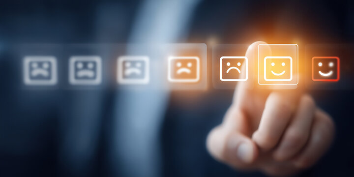 Business finger selects happy emoticon on customer feedback rating interface.
