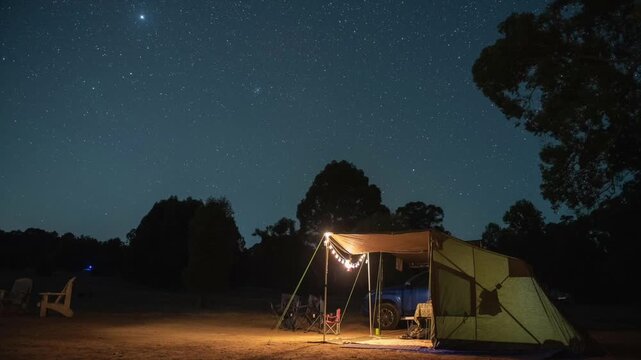 Camping at night time lapse with stars and festoon lights