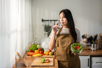 Asian woman eatting healthy salad and drink water in kitchen at home. 