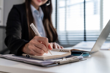 Close up of young businesswoman working and taking note in the office. 