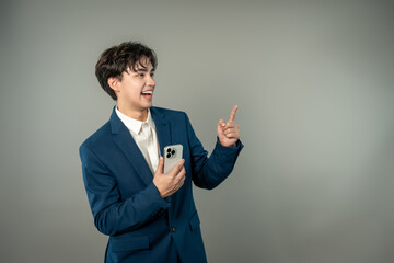 Asian businessman holding mobile phone and pointing in isolated background. 