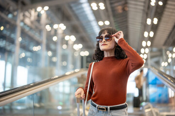 Asian young woman passenger walk in airport terminal to boarding gate. 