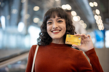 Asian young woman passenger holding credit card in airport terminal. 