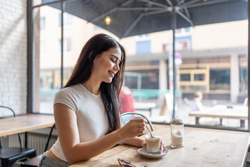 Mixed race woman drinking a cup of coffee at a table in cafe restaurant. 