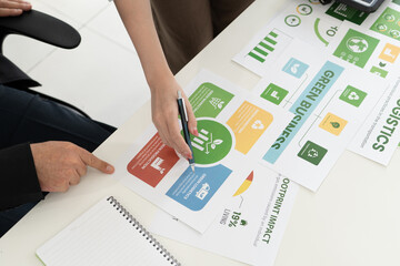 A diverse business team analyzing environmental charts and graphs in a collaborative meeting to create sustainable strategies in a modern office.