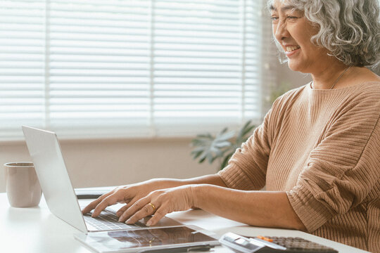 senior couple and documents with laptop for finance, budget planning or retirement annuity on sofa. Elderly man, woman or house with smile, computer or paperwork for pension fund or insurance