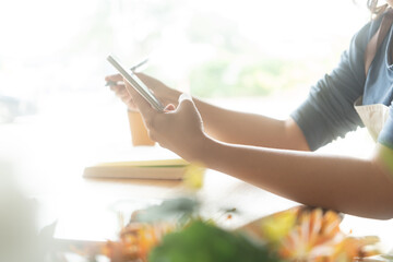 Asian female florist in apron smiling while designing a beautiful floral arrangement with her colleague in a flower shop. Concept of teamwork, creativity, floral business, and joyful workplace.