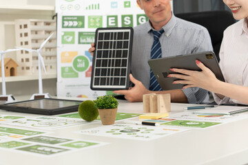 A diverse business team analyzing environmental charts and graphs in a collaborative meeting to create sustainable strategies in a modern office.