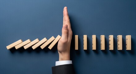 Risk Management and Prevention Concept with Hand Stopping Falling Wooden Dominoes