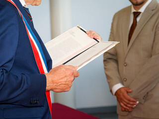 Élu portant l’écharpe tricolore lisant un registre officiel, représentation des institutions...
