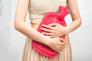 Woman using hot water bottle to relieve menstrual abdominal pain.