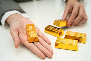 Asian woman holding gold bar in finance business.