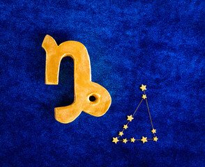 op view golden zodiac sign Capricorn on blue velvet background