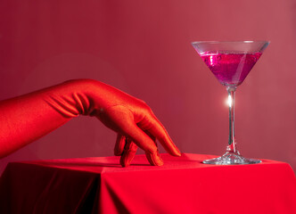 Red Gloved Hand Reaching for Pink Cocktail on Red Background