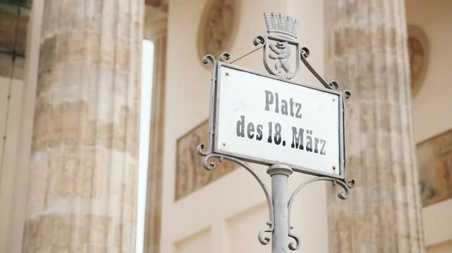 Schild "Platz des 18. M&auml;rz" mit dem Brandenburger Tor im Hintergrund