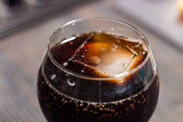 a large cube of ice in a glass of cola. close-up. whiskey with cola and ice