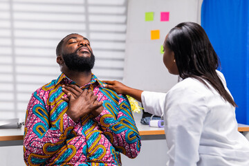 Obraz premium African female doctor provides comfort and care to a male patient experiencing chest pain or discomfort in hospital