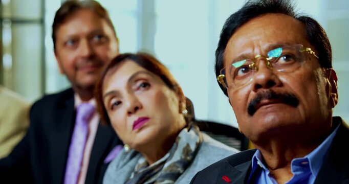 Indian five business people looking at presentation as closeup of senior Indian Asian businessmen attending training and reviewing slides while sitting across table inside modern corporate office
