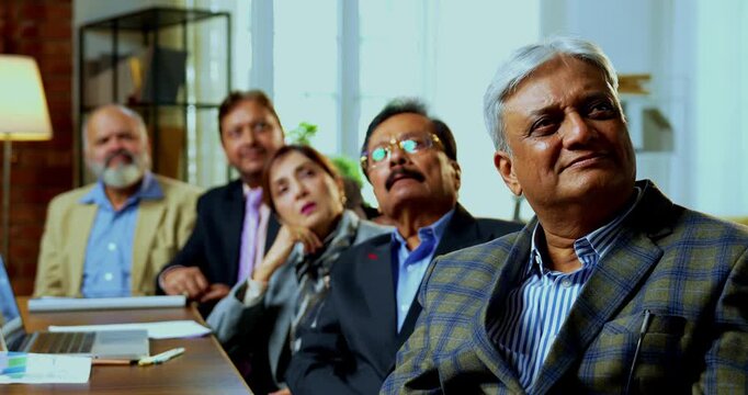 Indian five business people looking at presentation and clapping as closeup of senior Indian Asian businessmen applaud successful briefing while sitting or standing across table inside modern office