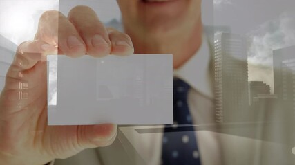 Composite video of mid section of caucasian businessman holing a business card against cityscape