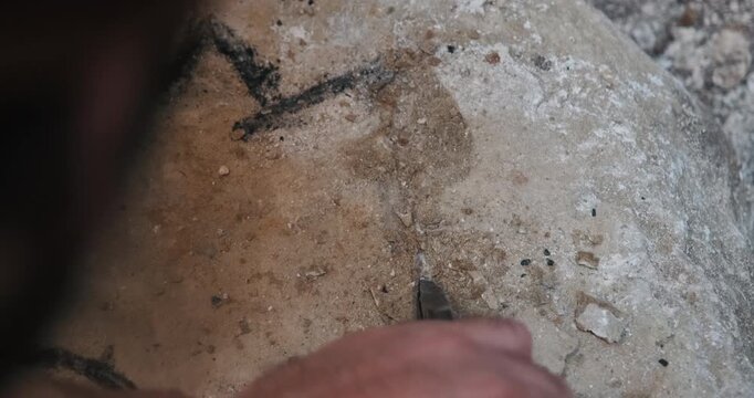 Traditional stone carving by hand, showing detailed craftsmanship with chisel and hammer.