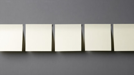 Blank sticky notes arranged neatly on gray surface, ready for writing or organizing ideas in clean workspace