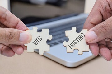 Hands holding two puzzle pieces labeled web and hosting. Website development, web hosting services, technology solutions concept.