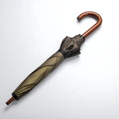 A closed, elegant umbrella rests diagonally across a white surface. The handle is curved wood and the shade appears a dark bronze
