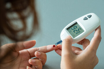 Woman's hands checking diabetes and hyperglycemia with digital blood sugar meter. Healthcare and medical concept	