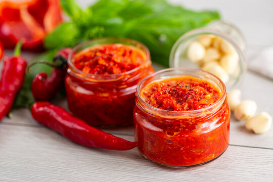 Fresh spicy sauce with chili peppers and herbs on table