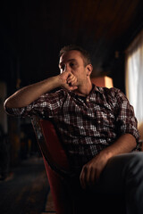 Man with headache, depression, sadness and loneliness sitting on a chair at home.