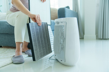 Woman changing filter of home air purifier.