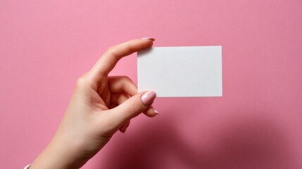 Hand holding a blank white card on a pink background for creative business id mockups, humorous personal identification concepts, and modern minimalist stationery presentation