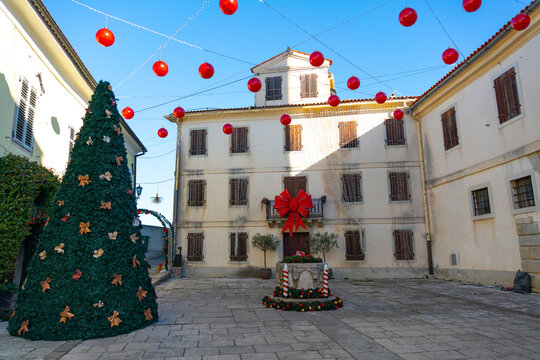 Festively decorated town square Trg Andrea Antico with a Christmas tree and red ornaments hanging above historic buildings in Motovun, Croatia