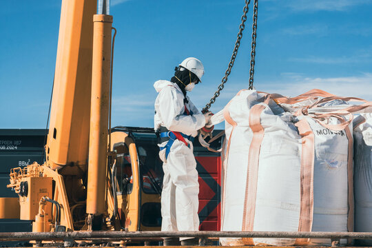 Crane slinger attaching mining product bags to a crane
