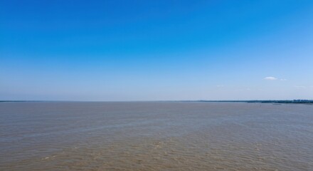 Wide, hazy view of a river under a clear sky