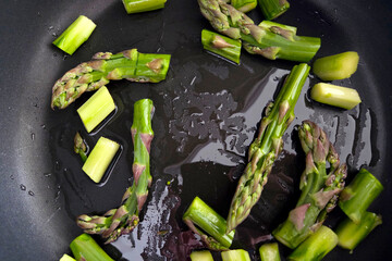 Fresh Asparagus Cooking in Black Skillet - Healthy Dinner Preparation Concept