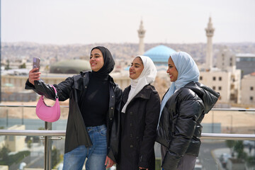 Three muslim women in front of the mosque taking selfie