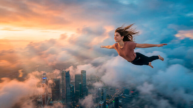 Young woman flying freely above city clouds at sunset