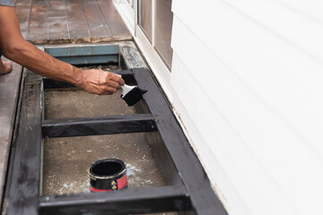 A professional painter is applying anti rust paint to a steel balcony outside a house.