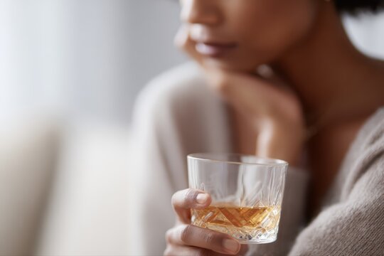 Alcohol abuse and depression, anxious woman drinking whisky alone at home