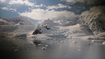 Antarctica , snow mountains reflected in the ocean with ice drifting and a blue sky with thick white clouds © Amelia