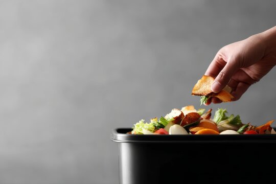 Food waste environment concept, person throwing leftover food into garbage bin