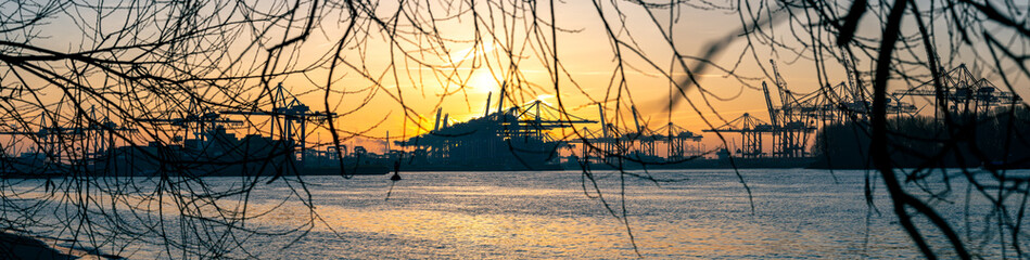 Panoramic widescreen shot of harbor facilities at the Elbe River in Hamburg at sunrise