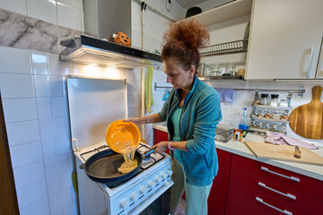 Woman pouring eggs into pan © Xalanx