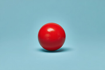 Vibrant red ball on blue background, simple yet striking visual