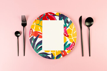 Top view of colorful plate, white card, black cutlery on pink background. Exotic plant plate,...